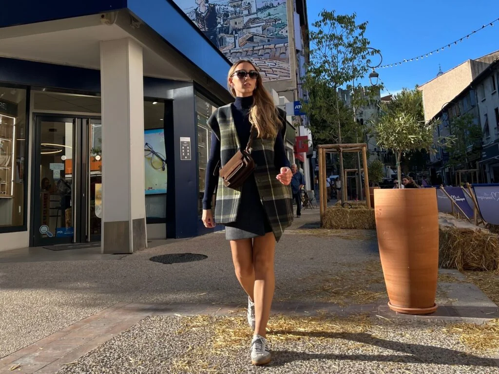 Lou porte un look hiver femme mix & match avec blouson check vert, col roulé marine et jupe portefeuille anthracite.