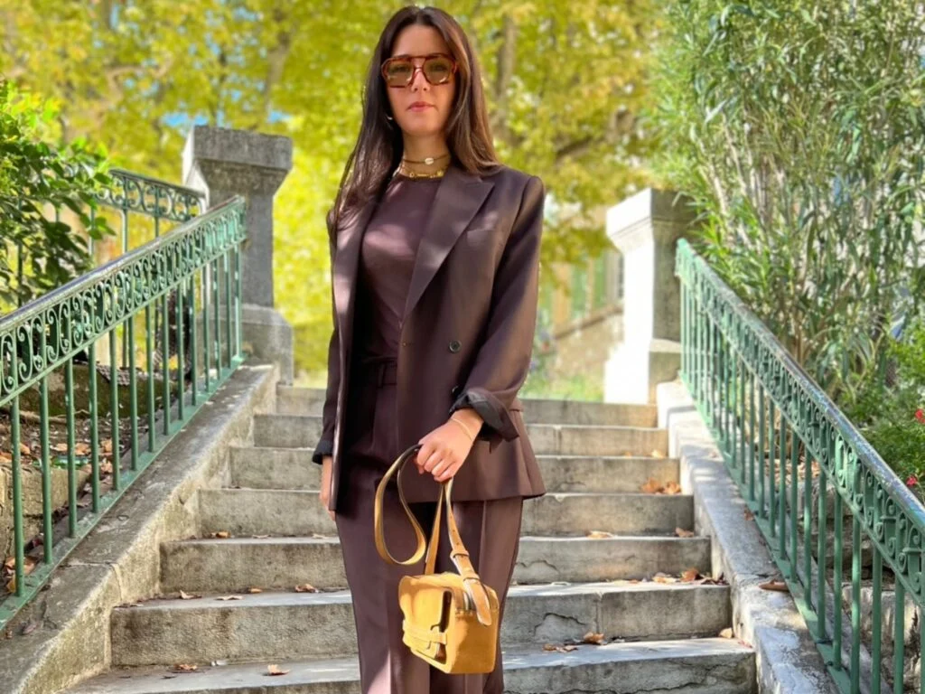 India porte un look hiver femme tailoring marron avec blazer oversize, pantalon fluide et sac suédé.